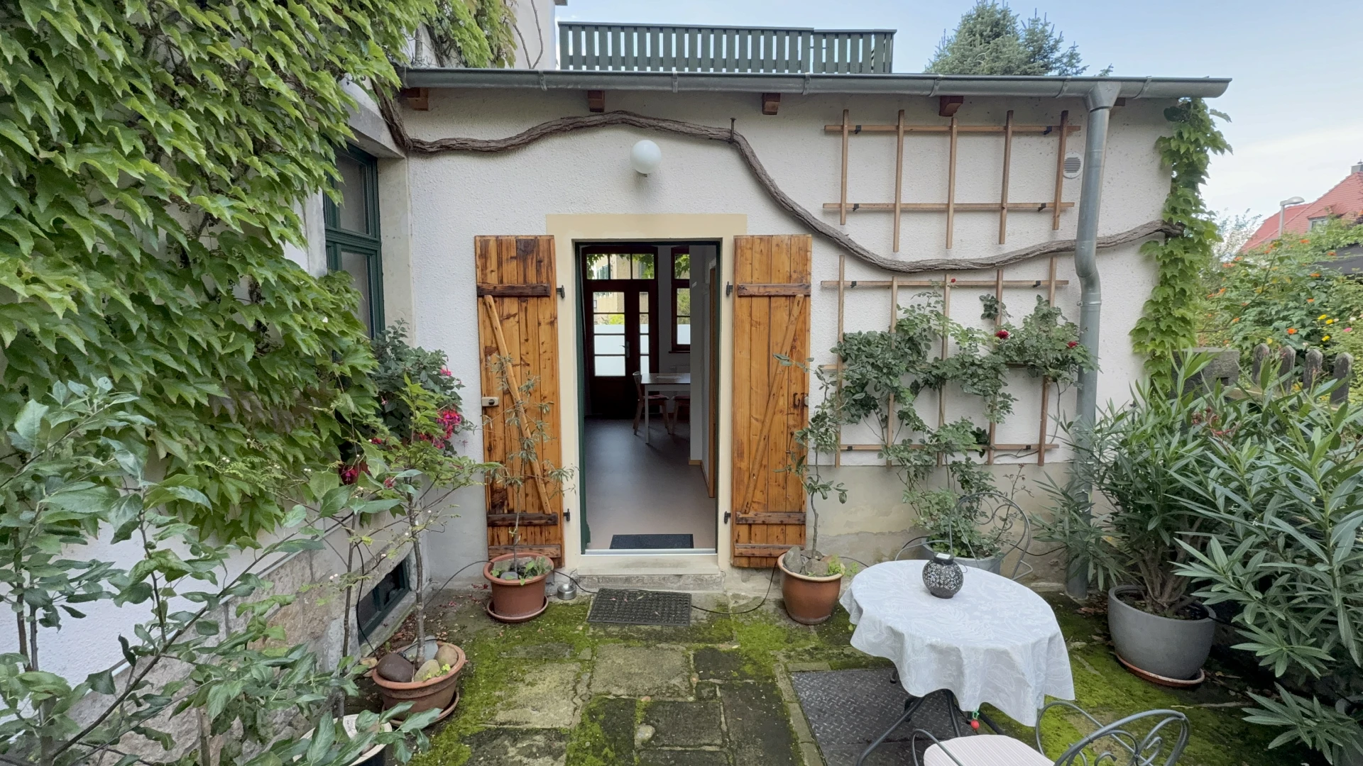 Sitzplatz im Hof mit Tisch, Gartentür und Pflanzen