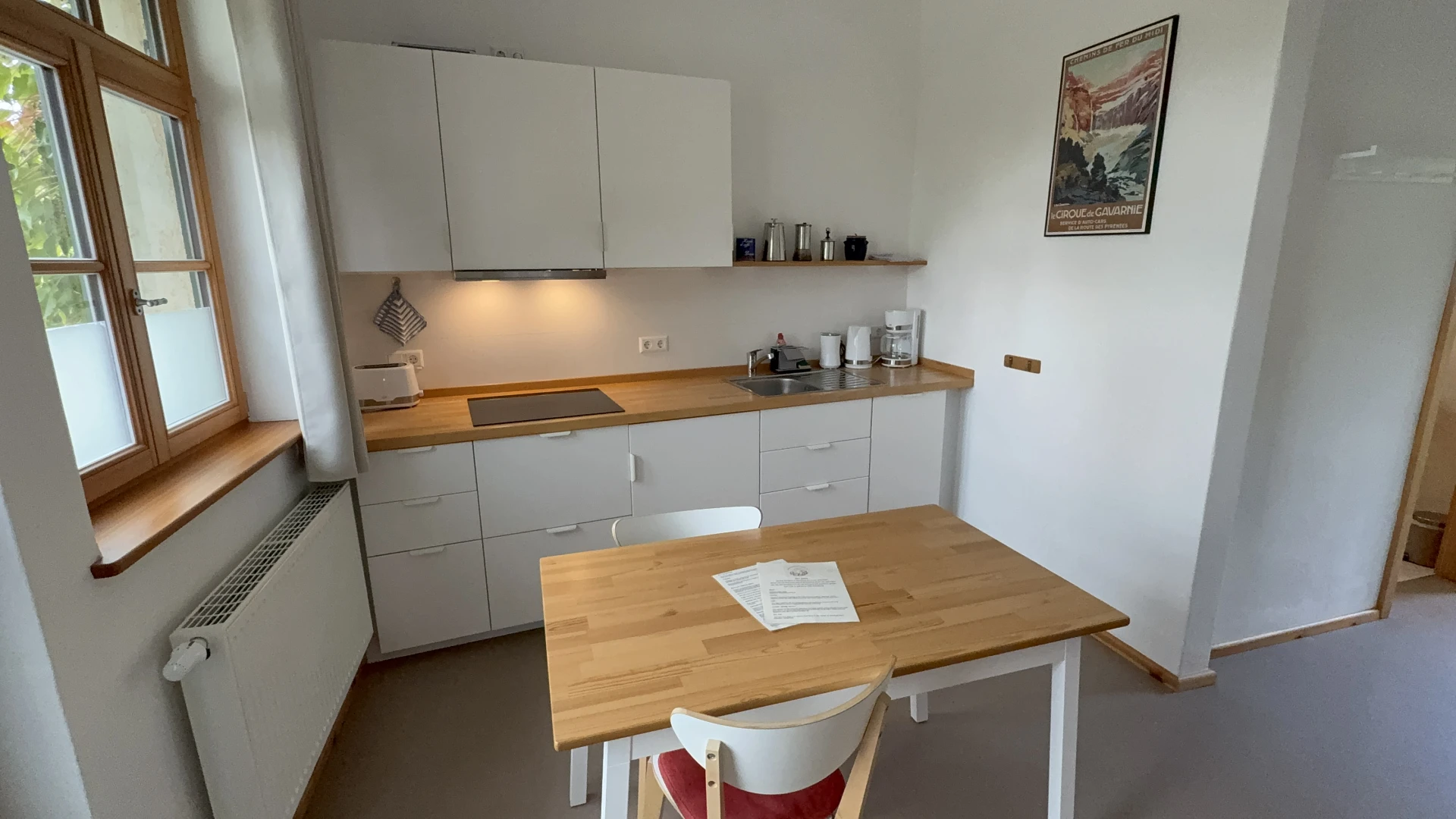 Küche mit Induktionskochfeld, Dunstabzugshaube, Espressomaschine und Esstisch